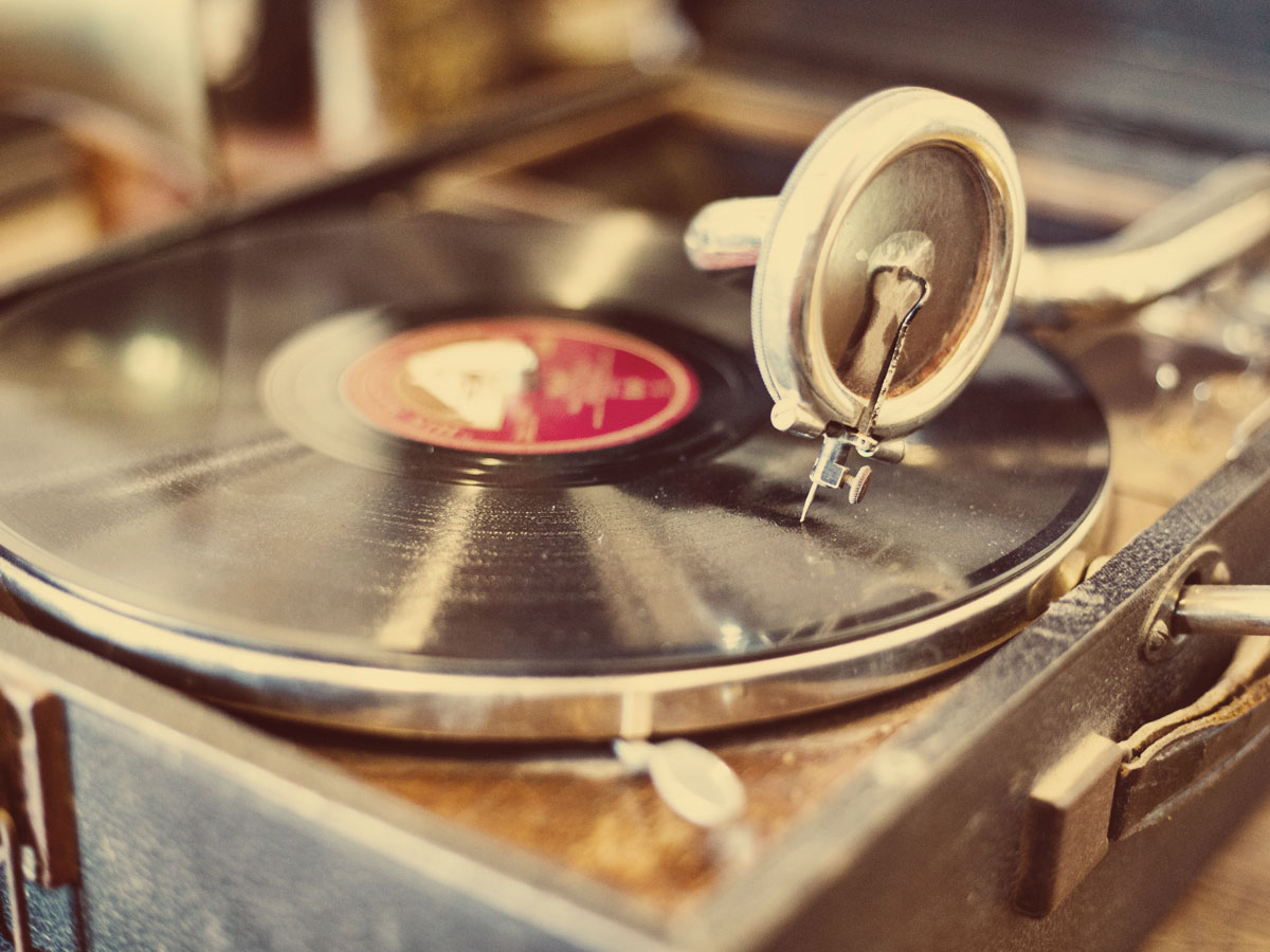 Eine Schallplatte dreht sich auf einem alten Plattenspieler mit silbernem Tonarm.
