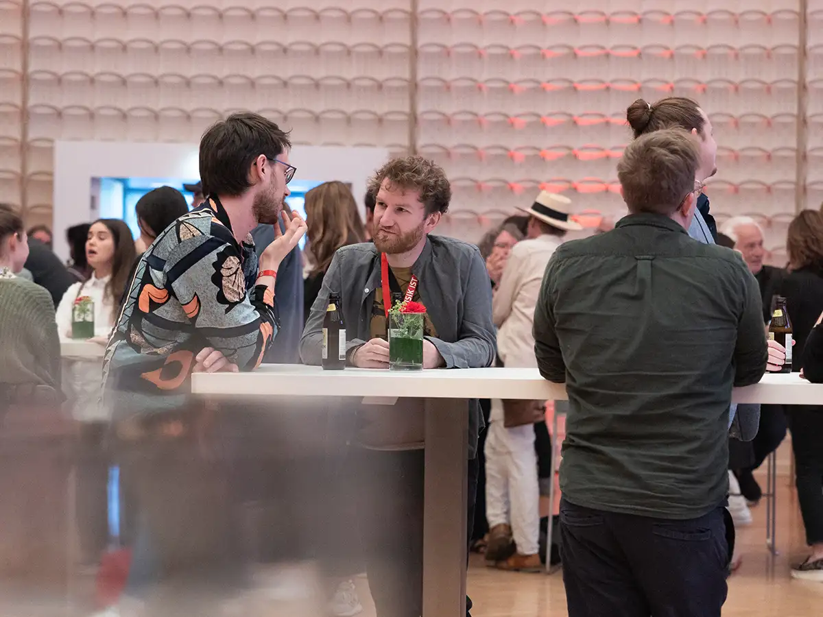 Menschen unterhalten sich an einem Stehtisch bei einer Veranstaltung.