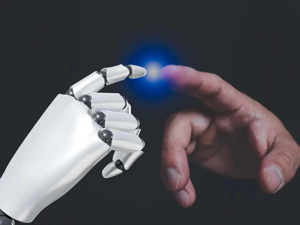 Eine Roboterhand und eine menschliche Hand berühren sich mit leuchtendem Punkt.