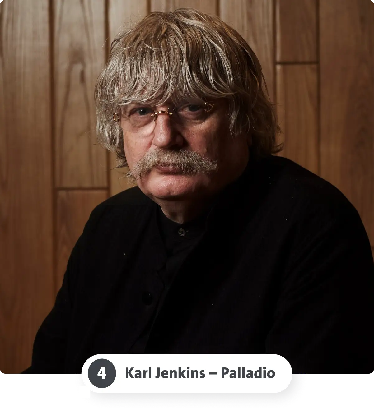 Älterer Mann mit Brille und Schnurrbart, schwarz gekleidet, vor einer Holzwand. Der Text darunter lautet „Karl Jenkins - Palladio“.