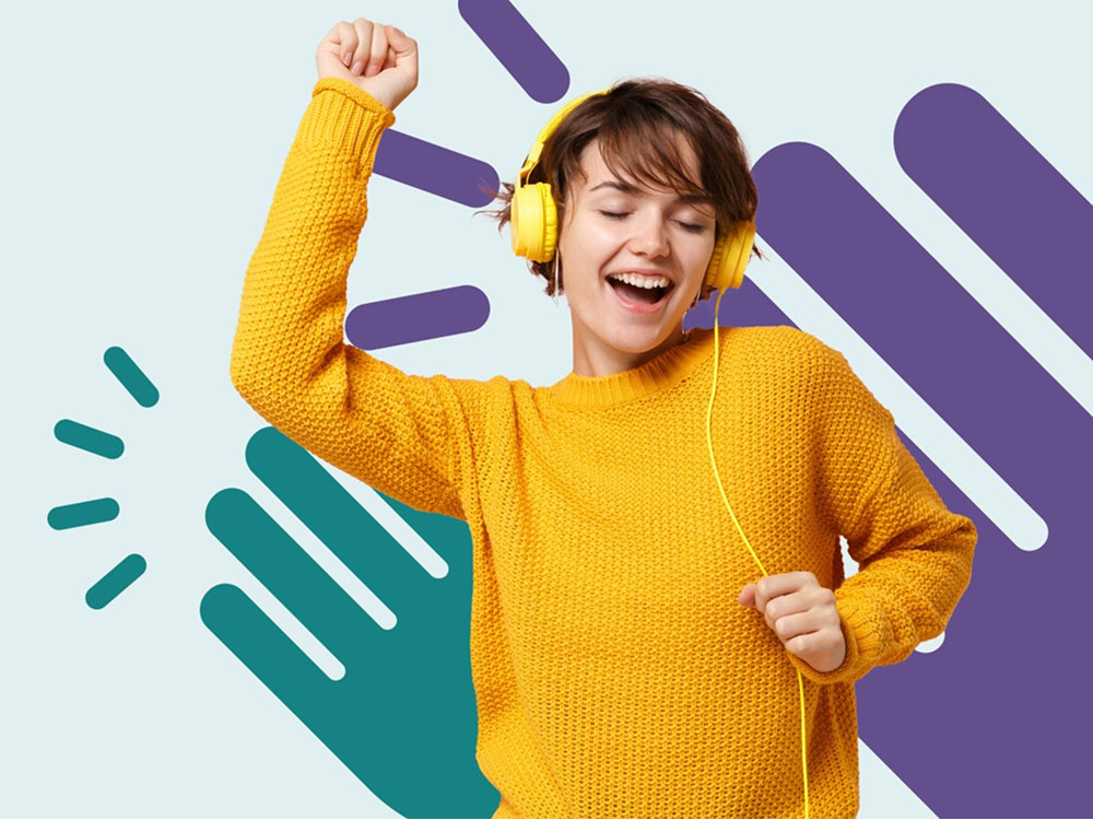 Person in gelbem Pullover tanzt mit gelben Kopfhörern vor buntem Hintergrund.