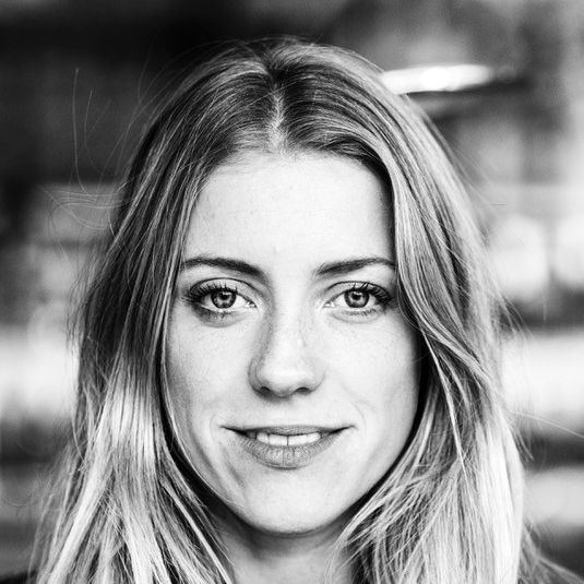 Eine Frau mit langen Haaren lächelt in die Kamera, schwarz-weiß Porträt.