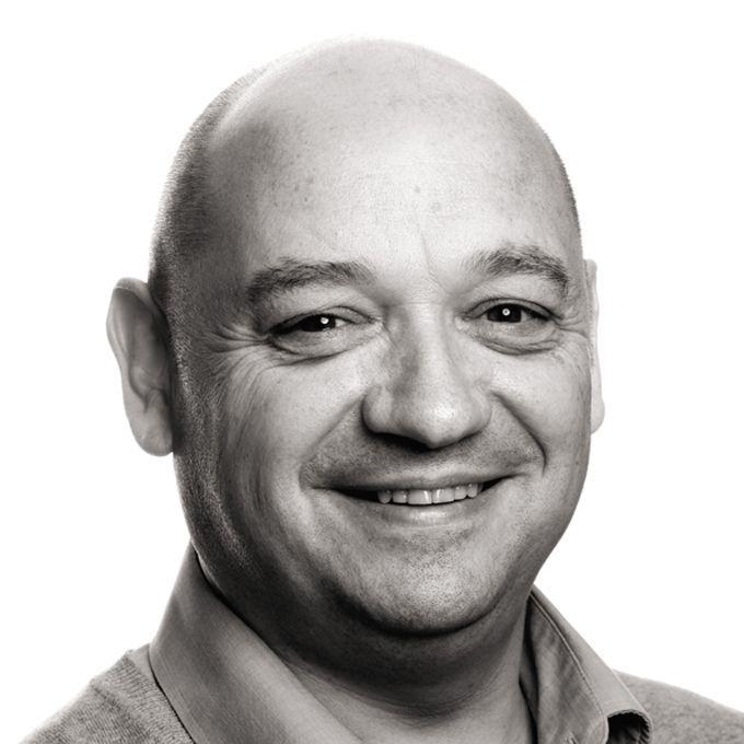 Porträt eines lächelnden Mannes mit Glatze in Schwarz-Weiß.