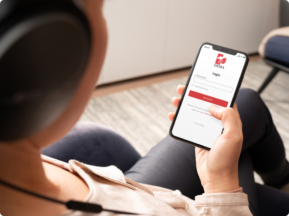 Person mit Kopfhörern hält ein Smartphone mit Login-Bildschirm in der Hand.