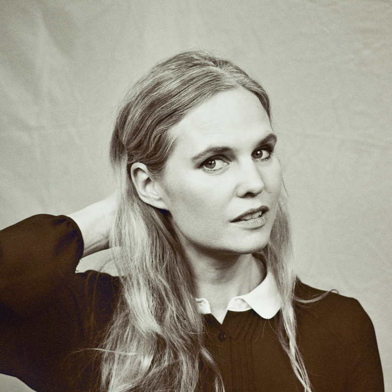 Schwarz-weiß Porträt einer Frau mit langen Haaren, die nachdenklich zur Seite schaut.