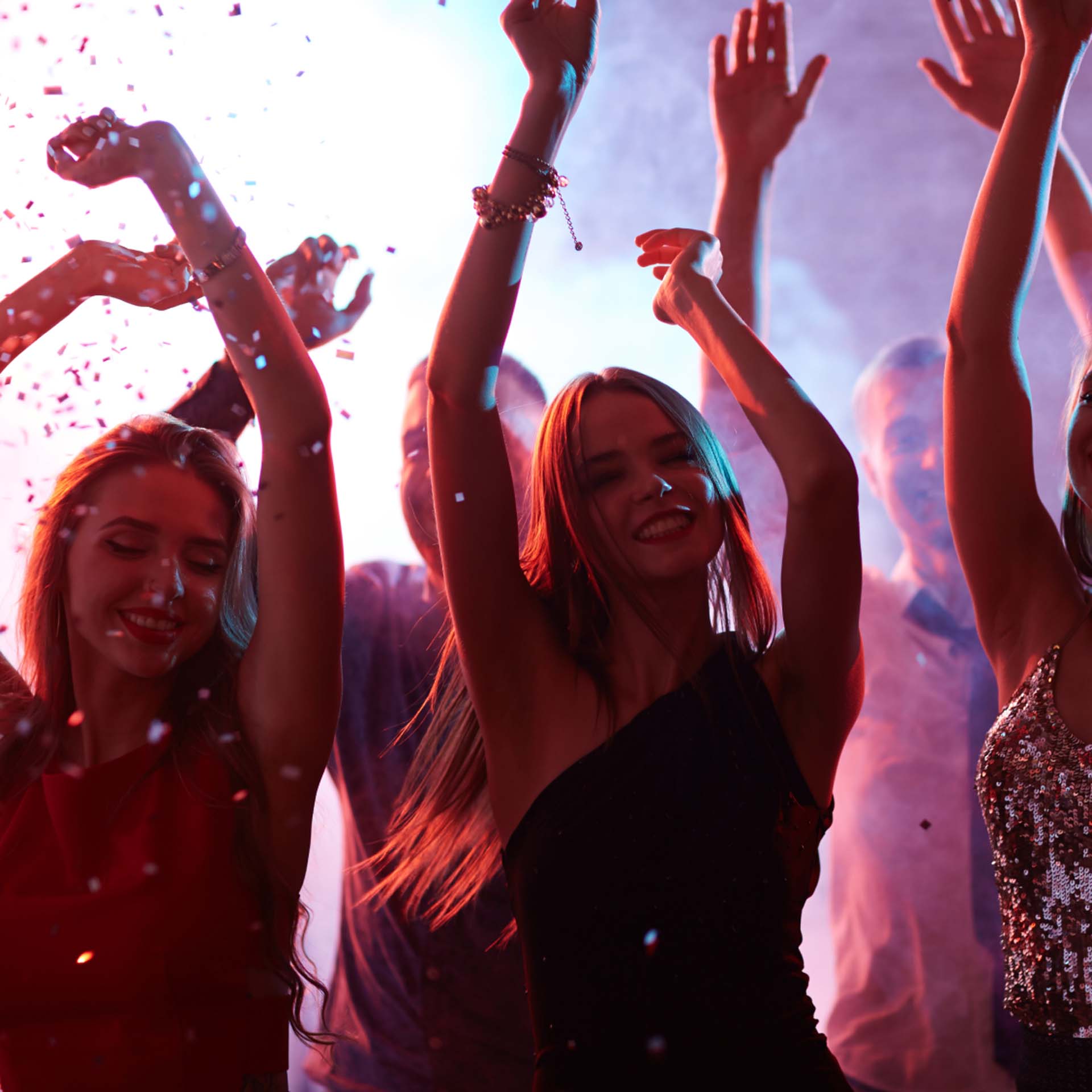 Menschen tanzen fröhlich in einem Club, bunte Lichter und Konfetti umgeben sie.
