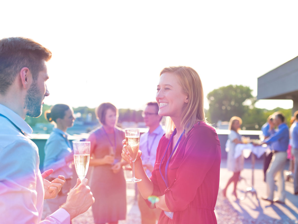 Eine Frau und ein Mann unterhalten sich mit einem Glas Sekt auf einer Party