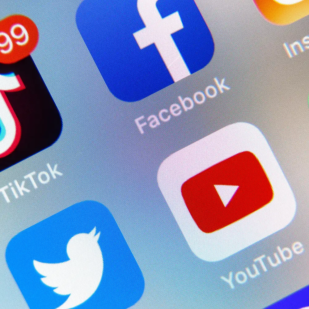 Symbole von TikTok, Facebook, Twitter und YouTube auf einem Smartphone-Bildschirm.