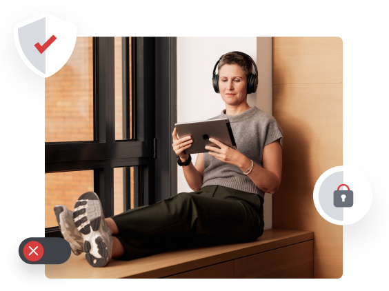 Eine Person mit Kopfhörern sitzt entspannt auf einer Fensterbank und liest auf einem Tablet.